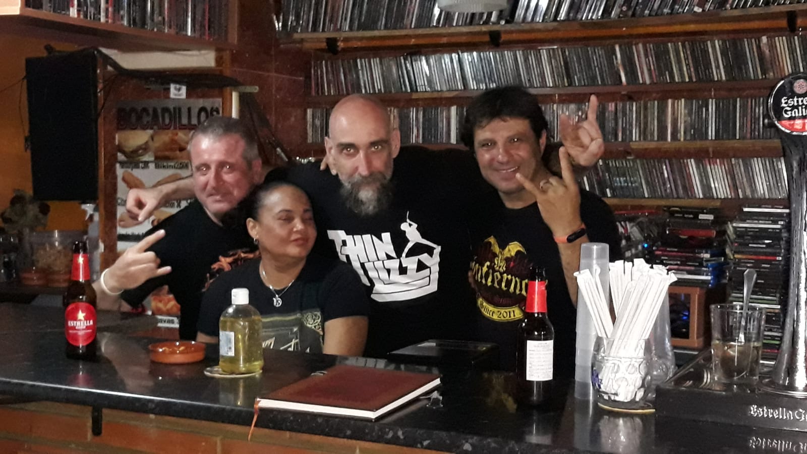 Personas en un bar con un ambiente relajado, rodeados de música y cultura del rock y metal.