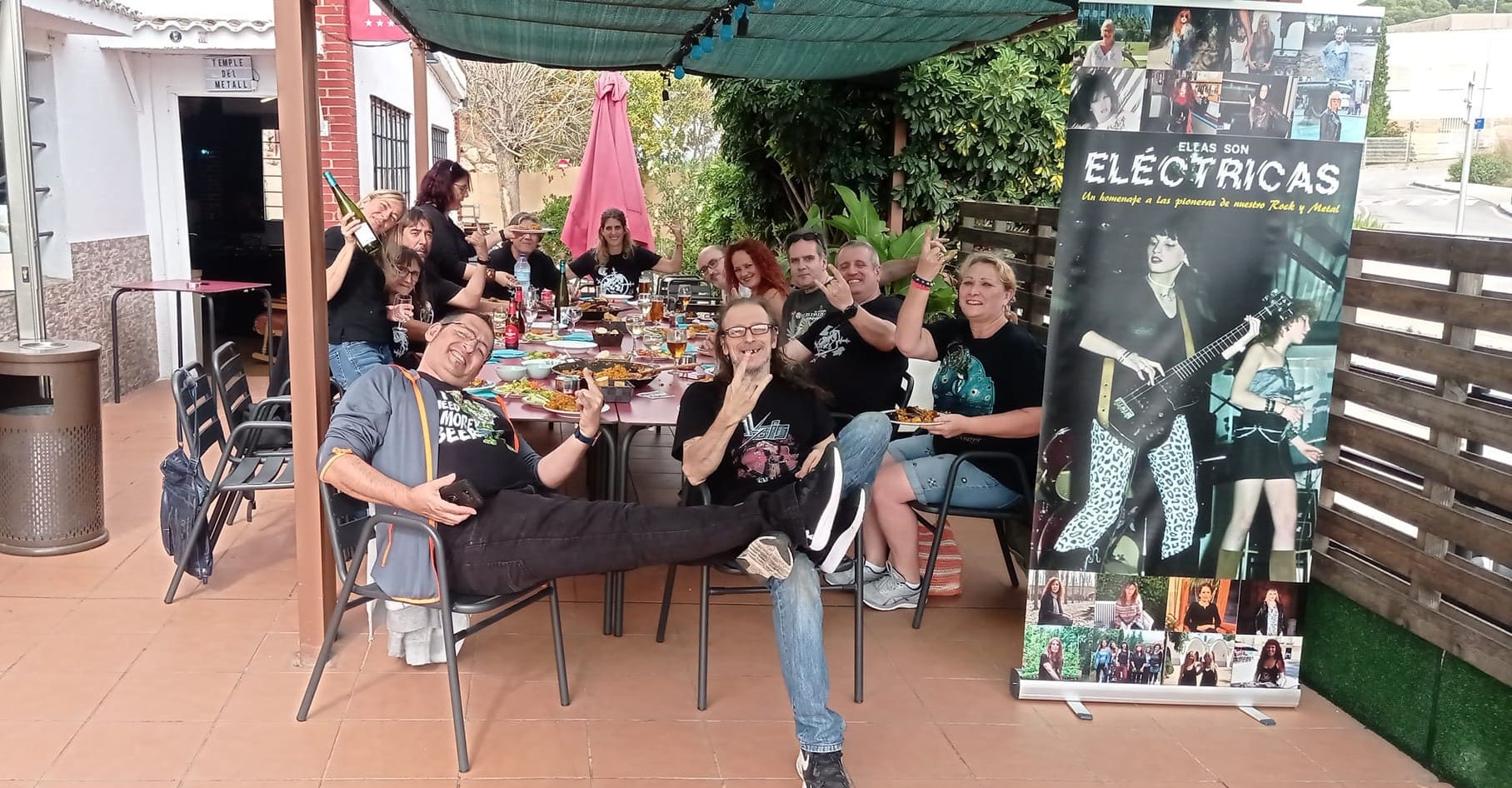 Un grupo animado disfrutando de una reunión social al aire libre, con gestos característicos del metal y un ambiente de camaradería.