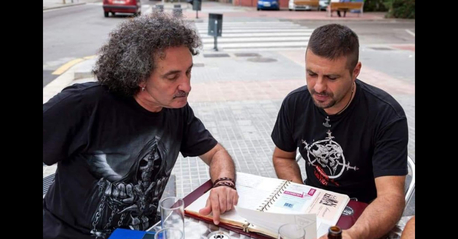 Dos personas sentadas en una terraza revisando documentos, simbolizando entrevistas a músicos.